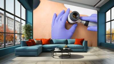 Doctor examining patient skin moles with dermoscope Wall mural