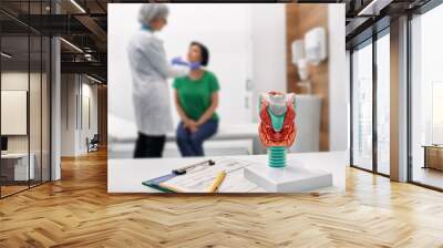 Doctor palpates of woman's neck for diagnostics of thyroid diseases. Thyroid gland exam and treatment Wall mural