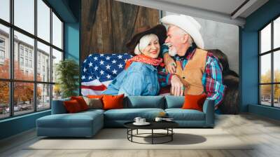 elderly couple, dressed in cowboy hats, laugh, taking each other's hands. Behind, on the couch lies the American flag, the celebration of America's Independence Day Wall mural