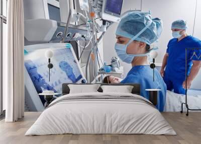 Hospital nurses checking on woman patient at intensive care unit and monitoring her health with medical equipment and sensors. ICU Wall mural