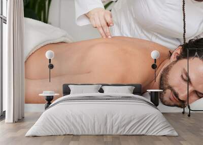 Male patient with acupuncture needles inserted in his back is receiving treatment chronic back pain in a traditional Chinese medicine clinic with acupuncturist Wall mural