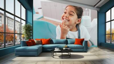 Mixed race little patient showing her perfect toothy smile while sitting dentists chair Wall mural