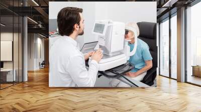 Practicing ophthalmologist examines a senior woman patient’s with special ophthalmic equipment in a modern clinic. Vision correction of elderly people Wall mural