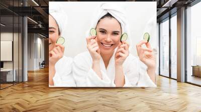 Super cucumber moisturizer face. Three beautiful women, with towels around head holding slices cucumber. Face mask for smooth skin Wall mural