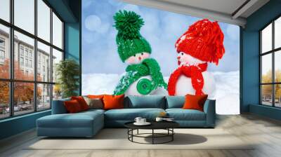 Two snowmen wearing a knitted hats  and scarves on winter blurred background. .  Winter holiday decor Wall mural