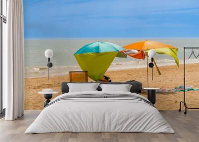 Two colorful sun parasols and a chair at a windy sunny beach in Algarve Portugal. Wall mural