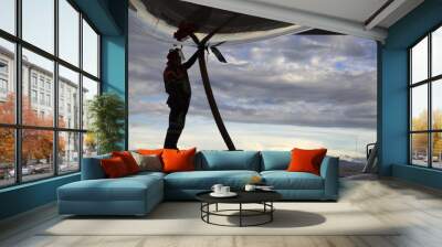 Airport staff operator refueling aircraft against blue sky Wall mural