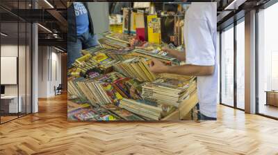 people looking for a book to buy in a second hand market Wall mural