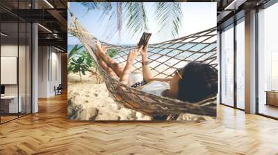 Happy woman using mobile phone in hammock Wall mural