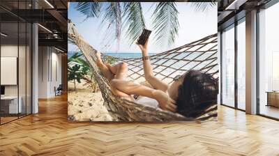 Traveler asian woman with mobile phone relax in hammock on summer beach Thailand Wall mural