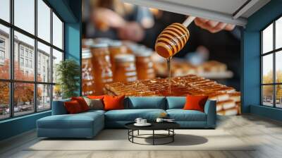 A close-up image showcasing a honey dipper drizzling golden honey over a neatly stacked pile of waffles. The warm, rich honey cascades over the waffles, creating a mouth-watering scene. Wall mural