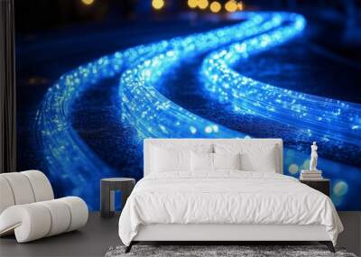 A close-up of glowing blue fiber optic cables curving across a dark surface. Wall mural