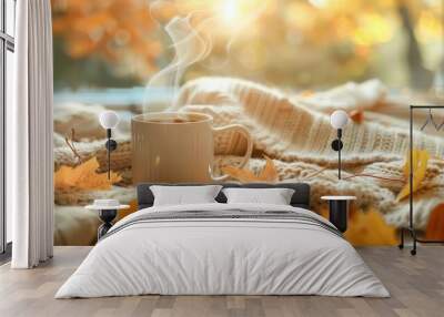 A steaming coffee cup with a background of autumn leaves and cozy blankets. Wall mural