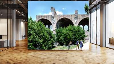 Rome, Lazio, Italy. July 25, 2017: Partial view of the ruins Basilica of Majencio and Constantine located in the ruins of the forum of the time of the Roman Empire, with two tourists visiting it Wall mural