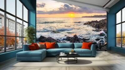 coast of the ocean at sunset. beautiful landscape with rocks in the water. gorgeous cloudscape above the sun and horizon. concept of calmness and mediatation Wall mural