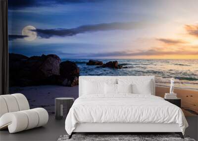 day and night time change concept above huge stones on the sandy beach at twilight. wonderful velvet season vacation. clouds on the blue sky with sun and moon above horizon. waves washing the shore Wall mural