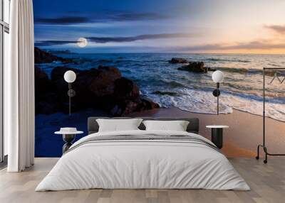 day and night time change concept above huge stones on the sandy beach at twilight. wonderful velvet season vacation. clouds on the blue sky with sun and moon above horizon. waves washing the shore Wall mural