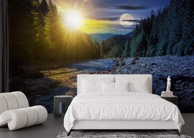 day and night time change concept. autumn landscape with sun and moon at twilight. rocky shore of the river that flows near the pine forest at the foot of the mountain in morning light Wall mural