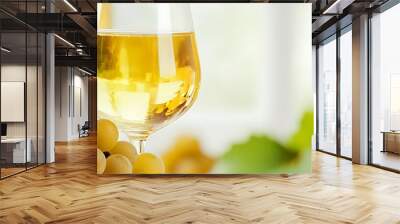 A glass of white wine with grapes in the foreground. Wall mural