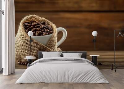 A white cup filled with roasted coffee beans is half-covered with a burlap sack, sitting on a wooden table. Wall mural