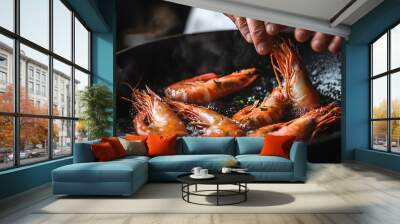 Closeup of chef's hands adding shrimp to a skillet with sizzling butter. Wall mural