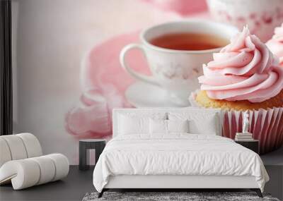 Two pink cupcakes with pink frosting on a white plate with a cup of tea. Wall mural