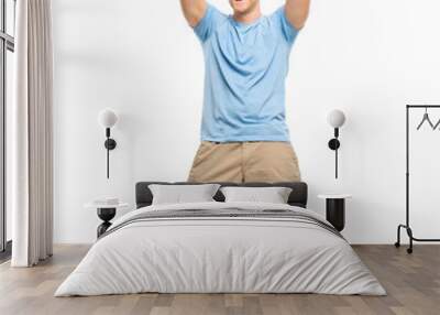 A handsome young man standing alone in the studio with his arms raised in celebration isolated on a PNG background. Wall mural