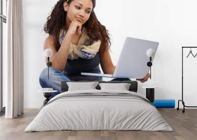 A Hispanic young college student looking at a laptop and reading e-books for university education and making internet research and online notes on a tech device isolated on a png background. Wall mural