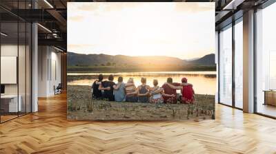 Back, hug and view with friends at lake together for outdoor holiday, travel or vacation in nature. Break, relax or trip and group of people embracing with horizon on water for calm, peace or quiet Wall mural