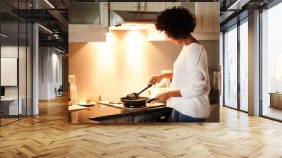 Black woman, pan and cooking on stove in home, frying and meal preparation in kitchen. Female person, apartment and nutrition in food, diet and wellness for cuisine on gas for dinner routine in house Wall mural