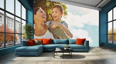 Blue sky, kid and woman with piggyback in nature for travel, holiday and bonding together in forest. Low angle, fun and mother with daughter in park for support, love or child development on vacation Wall mural