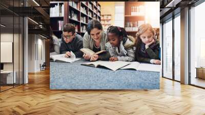 Children, education and teacher with books on library floor for reading, learning and teaching. Study, school and woman with kids for storytelling, help and fantasy, language and skill development Wall mural