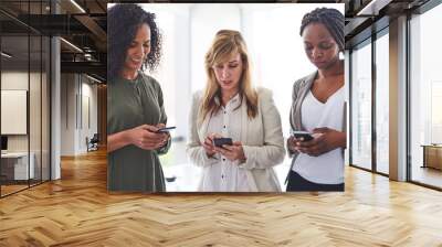 Collaboration, diversity and phone with business women in office together for communication or networking. App, social media or text message with employee people in workplace for contact or update Wall mural