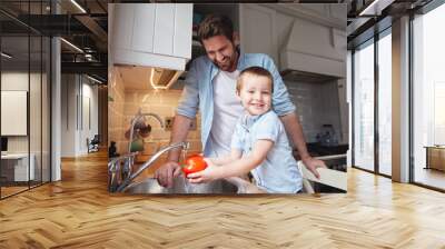 Cooking, father and child wash vegetables for food, nutrition or learning healthy diet in portrait. Face, dad and happy kid clean pepper in kitchen for hygiene, wellness or organic meal prep in home Wall mural