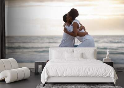 Couple, engagement and sunset at beach for holiday, travel and date in summer while bonding together. Man, woman and marriage proposal by ocean for vacation, love and romance with hug, water and sand Wall mural