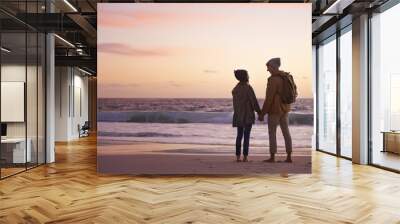 Couple, holding hands and love at sunset by water, ocean waves and peace for romance in relationship. People, back and security in marriage, sea and travel together on vacation or holiday for date Wall mural