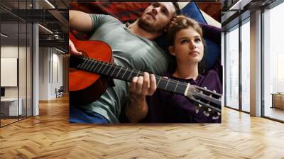 Couple, relax and guitar in home for music, bonding and love together on floor with blanket or pillow. Man, woman and playing instrument in apartment for romance, relationship or comfort with support Wall mural