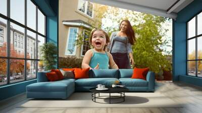 Excited, toddler and mother outdoor in backyard for play, fun and adventure on summer weekend. Young kid, happy and woman chasing in garden for explore environment, growth and development at home Wall mural