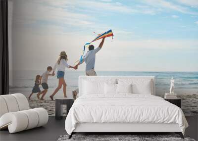 Family, flying kite and holding hands on beach together for holiday, travel or vacation in summer. Energy, love or running with mother, father and kids on sand at coast by ocean or sea for bonding Wall mural