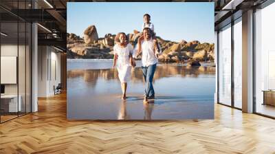 Family, portrait and walking at beach for bonding, travel and vacation with support, care and carrying. Parents, children and holding hands for relationship, relax and holiday with blue sky as people Wall mural