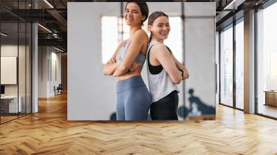 Gym, friends and women with smile on back to back for fitness, exercise and workout break. People, portrait and happy or confident with body building for wellness, wellbeing and self care on training Wall mural