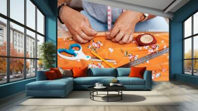 Hands, tailor and sewing cloth on table at home for manufacturing, production and handmade costume. Creative, fashion designer or dressmaker with garment, needle and textile with details for boutique Wall mural