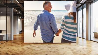 Happy couple, beach and holding hands on holiday, travel or summer vacation for love in nature. Mature man, woman and back view at ocean on adventure, support or laugh on date together outdoor at sea Wall mural