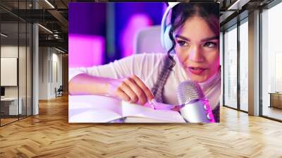 Influencer, ASMR and book with microphone, whisper and neon lights with podcast, content creation and tech. Home, broadcast and pen writing for stress relief with woman and recording for sound Wall mural