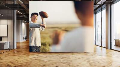 Kid, dad and throw with football on grass field for outdoor sports, exercise and child development. Smile, man and happy with son in nature for teaching, practice and bonding together on fathers day Wall mural