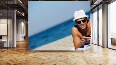 Man, beach and smartphone in portrait on holiday with ocean on seashore with blue sky in summer for peace. Male person, vacation and relax with phone for memories in cancun with wellness on trip Wall mural