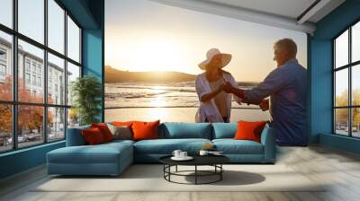 Mature, happy couple and dancing with beach in sunset for love, bonding or support in nature. Man, woman or lovers enjoying romance or holding hands for outdoor holiday or summer by ocean coast Wall mural