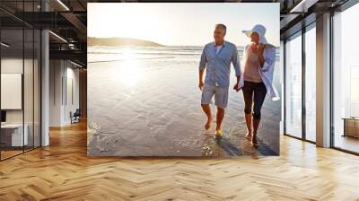 Mature, happy couple and walking with holding hands in beach sunset for love or bonding together in nature. Man, woman or lovers enjoying stroll on water for outdoor holiday or summer by ocean coast Wall mural