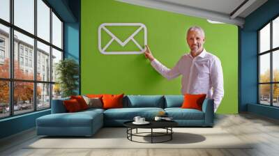 Mature, happy man and portrait with email, icon or envelope for communication, message or online service. Businessman, employee or pointing with smile or symbol for presentation on green background Wall mural