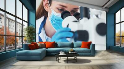 Microscope, scientist and innovation in research laboratory for medicine, biology and pharmaceutical in Denmark. Female person, doctor and tech with ppe mask for pathology, science and mpox vaccine Wall mural